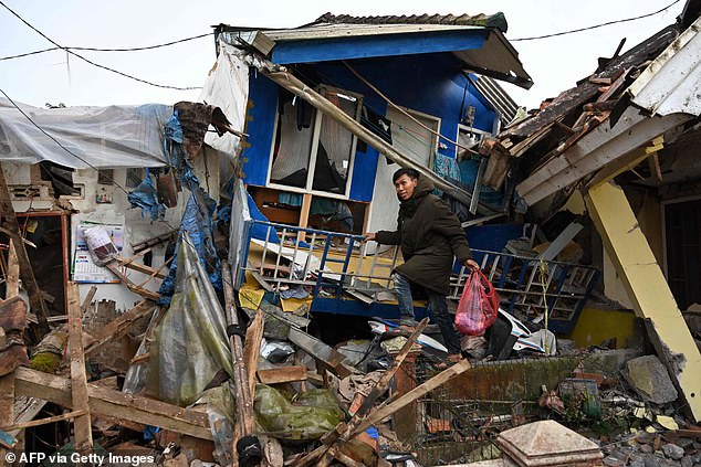 A man salvages items from a damaged house as he walks amongst the rubble in Cianjur on Tuesday