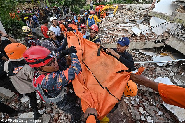 Rescue workers carry the body of a victim in Cianjur following the earthquake on Tuesday