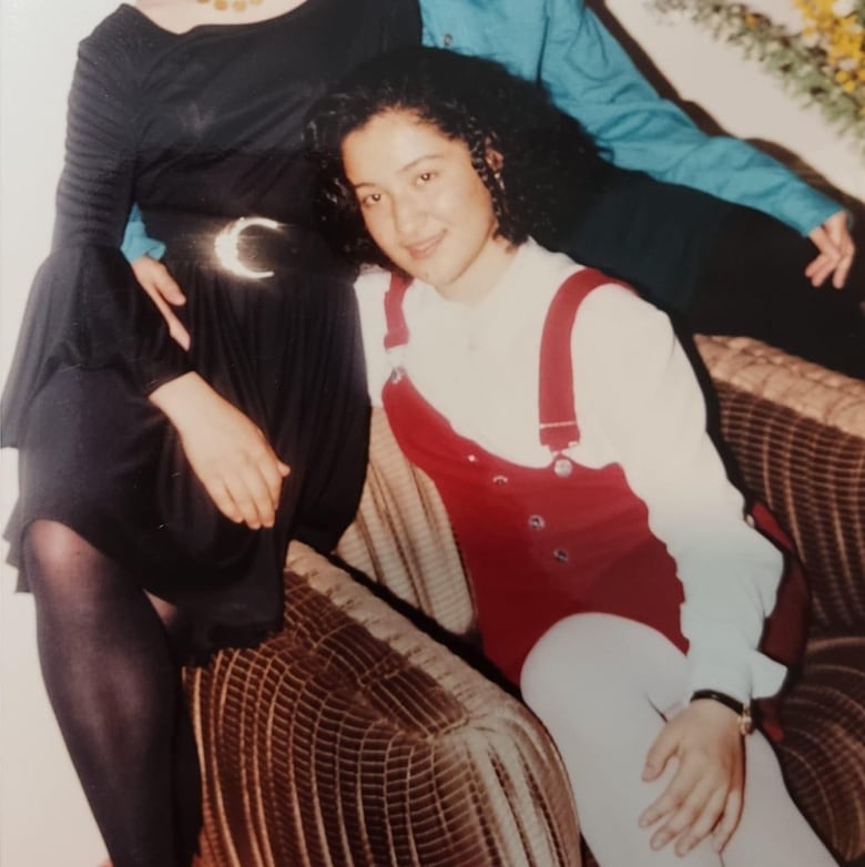 Three girls sit on a chair smiling.