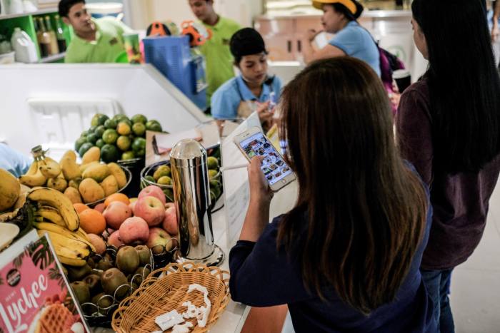 A customer uses the Globe Telecom mobile payment application on her smartphone at a cafeteria