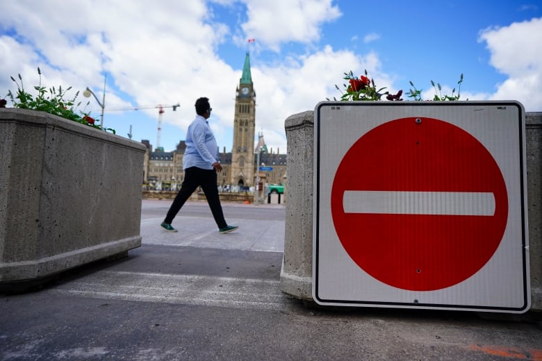 Someone passes by a road closure sign in front of Parliament Hill.