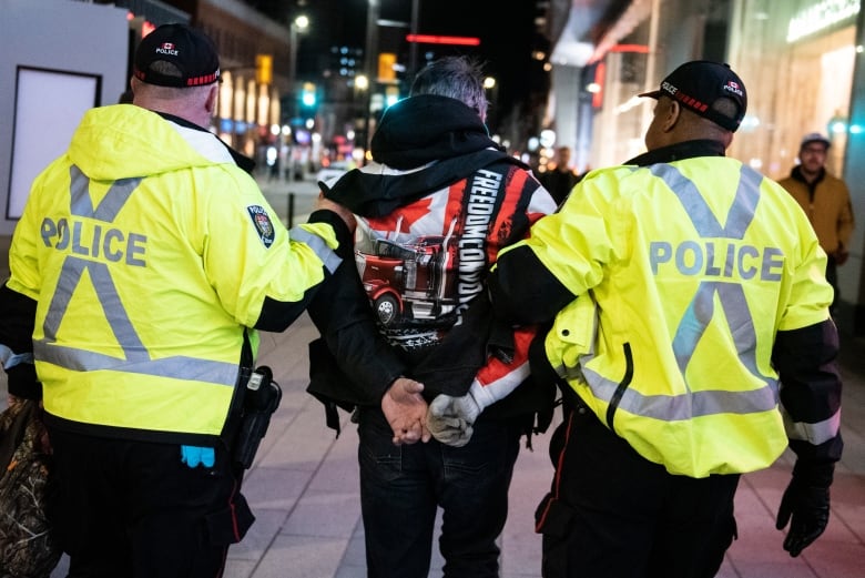 Two police officers escort someone away.