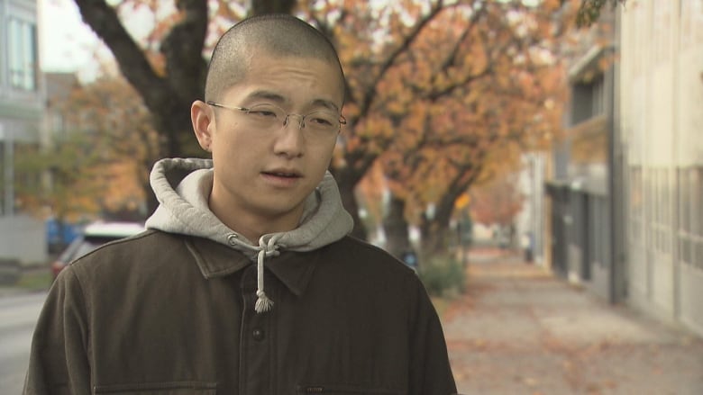 A bald man looks at the camera in a fall setting.