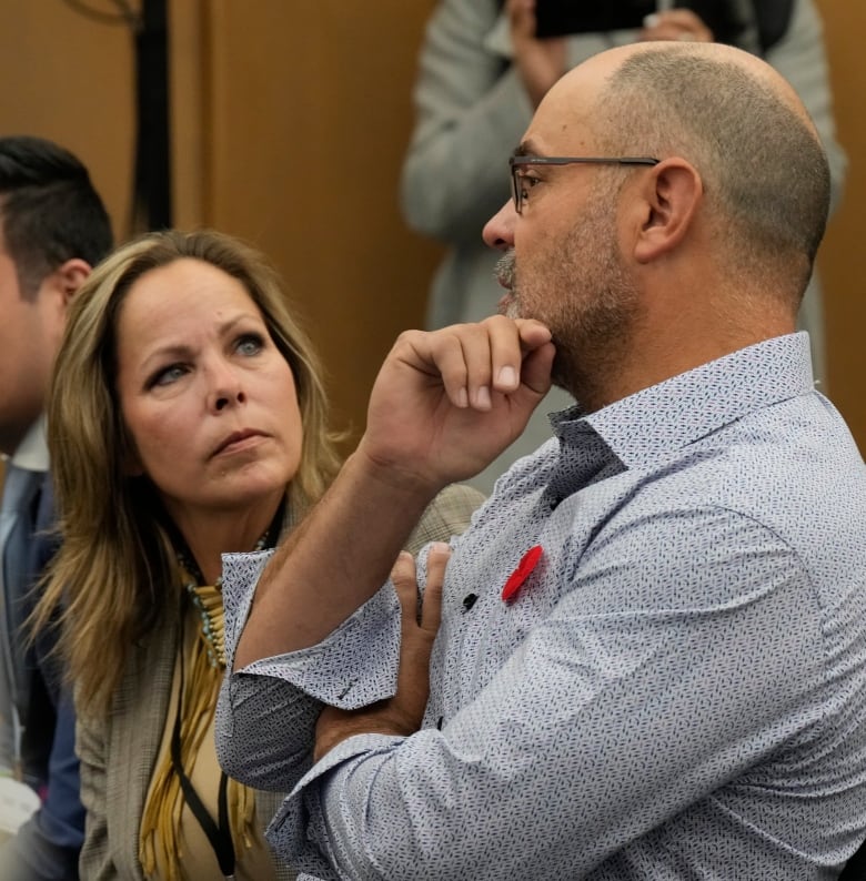 A man and woman speak while seated in a meeting room.