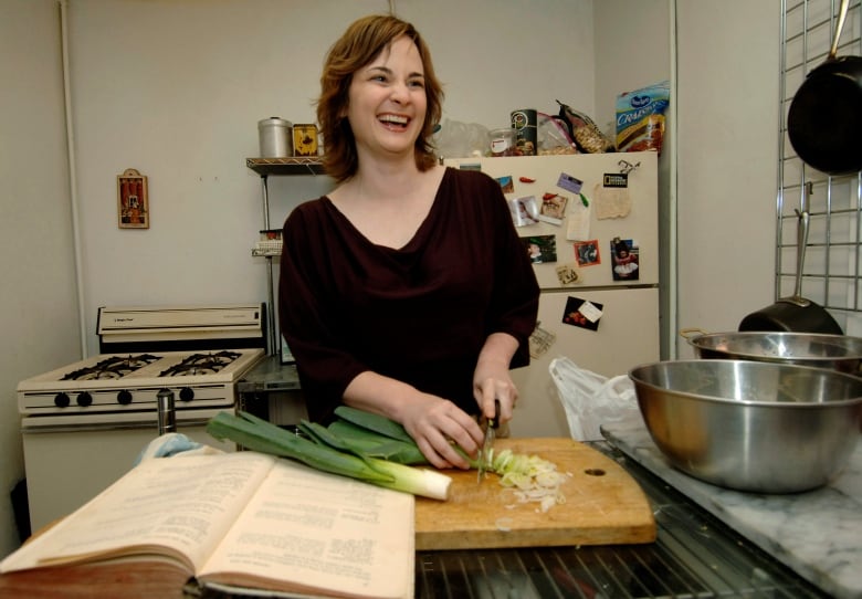 Laughing woman chopping green vegetables on a wooden butcher's block. 