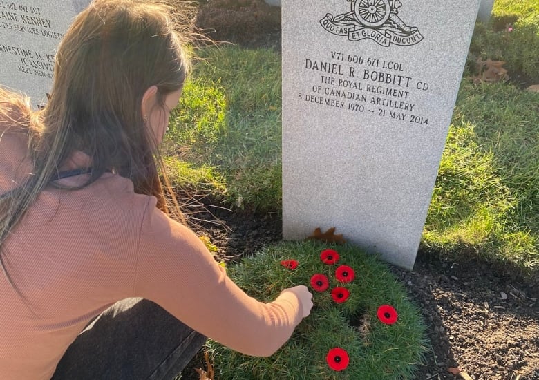 A woman at a grave decorated with poppies.