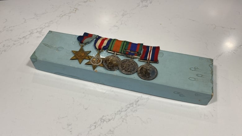 Medals from the second world war are on a cardboard jewellry box.