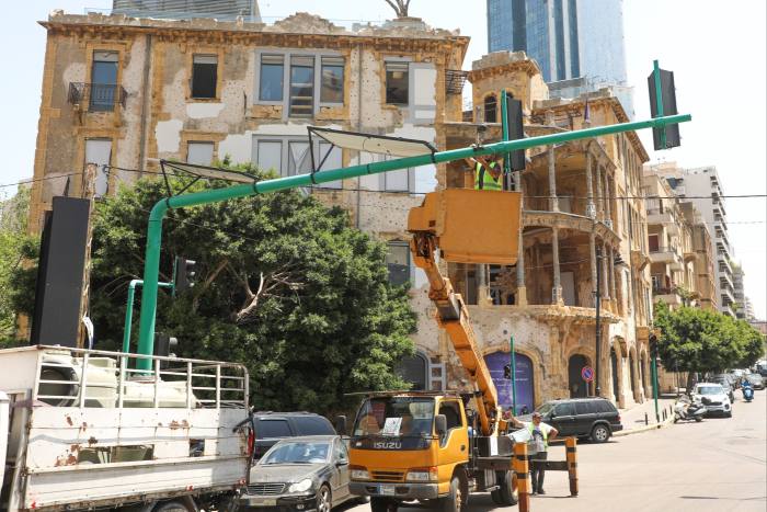 A worker at Rebirth Beirut installs solar panels on traffic lights in May