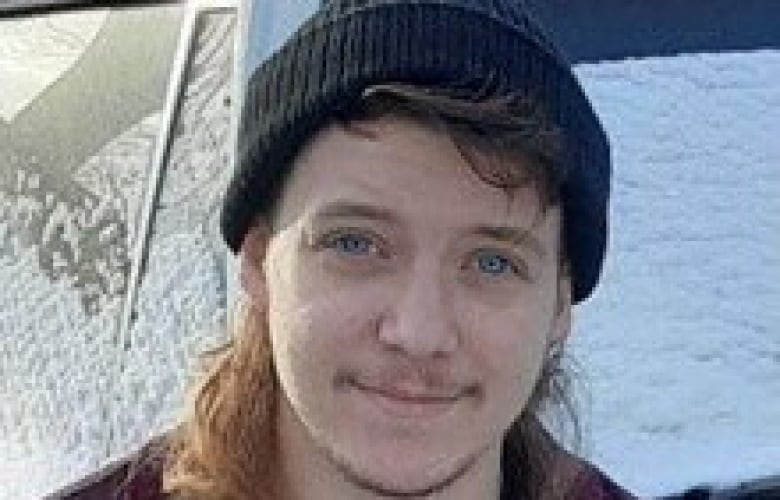 A young man in a wool cap smiles for the camera.