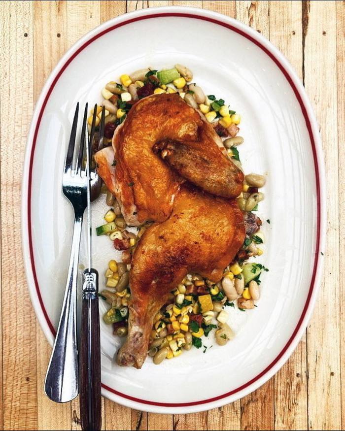 Roast chicken on a bed of beans and pulses on a plate at New York’s Houseman restaurant