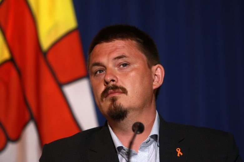 Headshot of man in front of Nunavut flag.