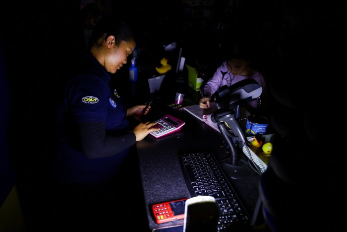 A woman makes calculations as she assists a customer using a rechargeable light. South Africa’s decrepit coal stations are struggling to keep the lights on, with rolling power cuts of up to five hours a day crippling industry and making life unbearable