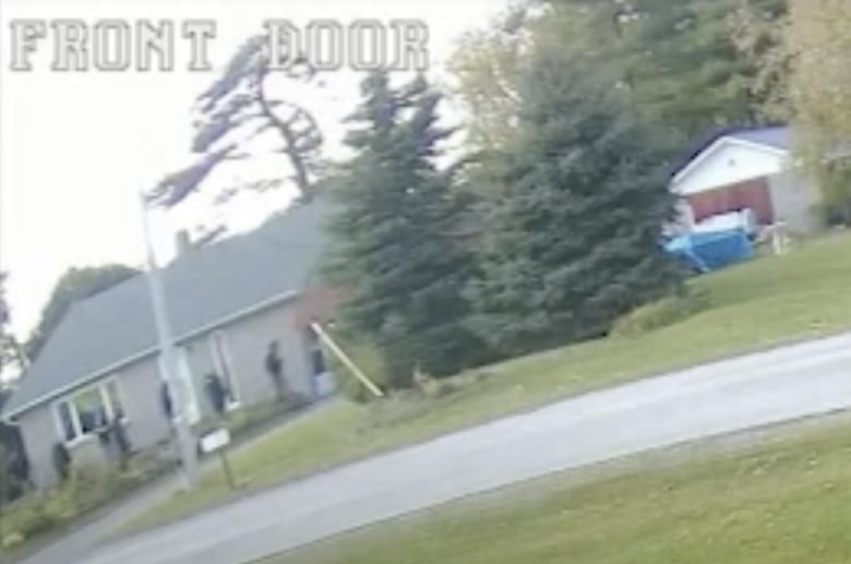 A row of people walk by a house.