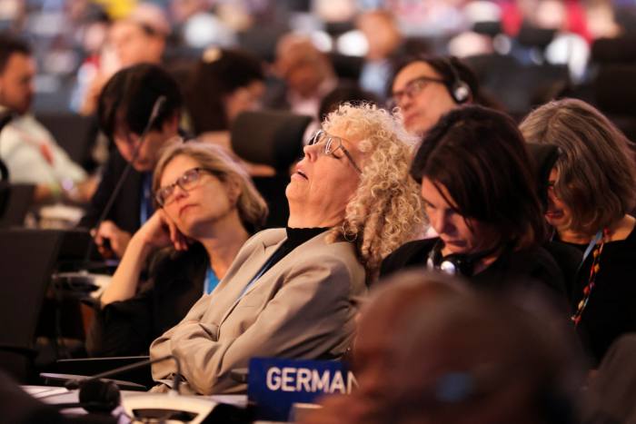 People attend the closing plenary at the COP27 climate summit taking a nap