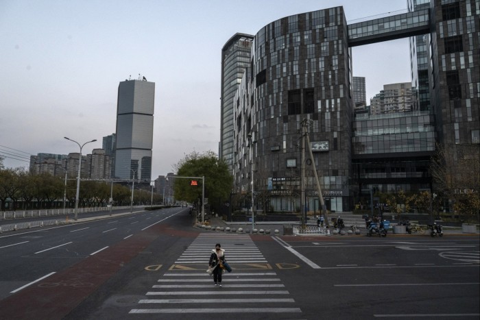 A woman crosses a nearly empty road in Beijing’s central business district during what would normally be rush hour