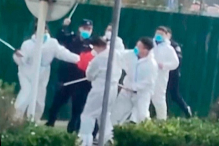 Security personnel attack a protester with clubs at a factory compound operated by Foxconn in Zhengzhou, Henan, China, in November 2022