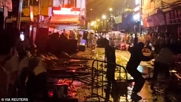 Demonstrators protesting over coronavirus disease (COVID-19) restrictions throw glass bottles towards riot police in Guangzhou, Guangdong province, China in this screen grab taken from a social media video released on November 30, 2022