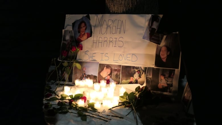 Candles stand beside a homemade sign saying "Morgan Harris. She is loved."