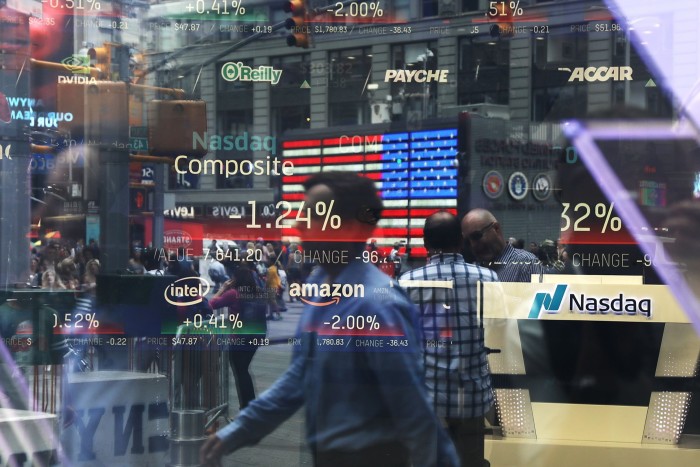 People are reflected in the window of the Nasdaq MarketSite in Times Square