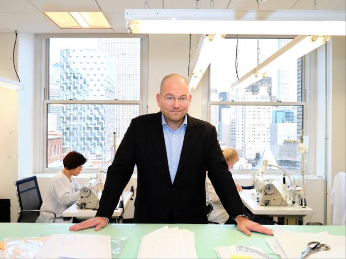 Alex Bolen in a suit stands in front of a table