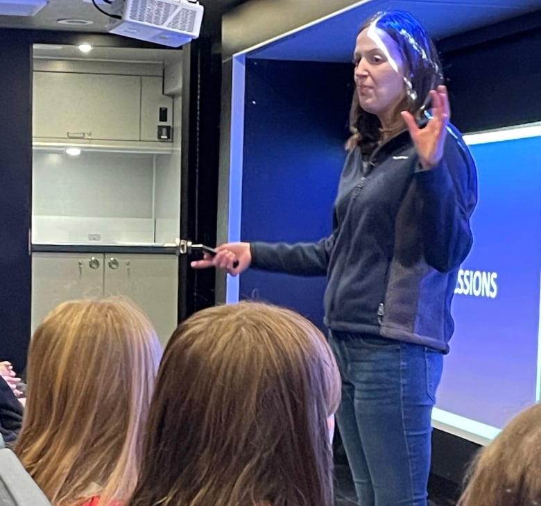 A woman does a presentation in front of a class of young students.