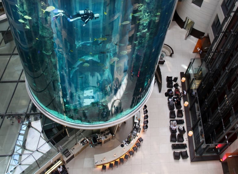 A unique elevator with a water-filled enclosure is seen in the centre of a building's atrium.