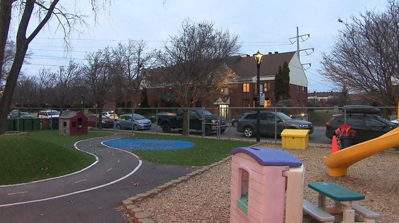 A large daycare playground in a Montreal residential neighbourhood with a yellow slide, small pink house and picnic table.