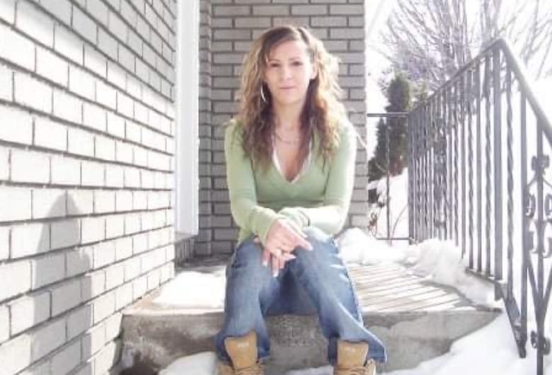 A picture of a woman sitting on the front steps of a house.