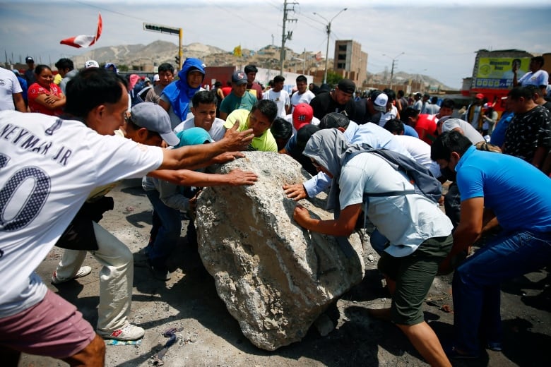 Supporters of ousted Peruvian President Pedro Castillo work together to roll a boulder onto the Pan-American North Highway during a protest against his detention, in Chao, Peru, Thursday, Dec. 15, 2022. 