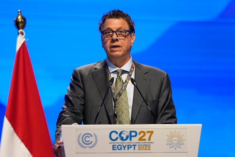 A man in a suit speaks at a lectern.