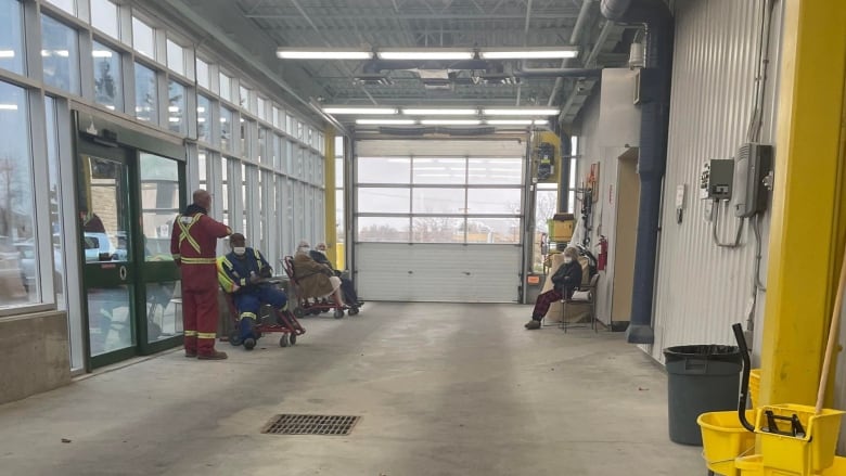 Five people are seated inside an ambulance bay that looks like the inside of a garage.