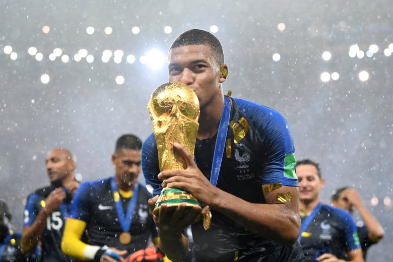 A soccer player kisses the World Cup trophy.