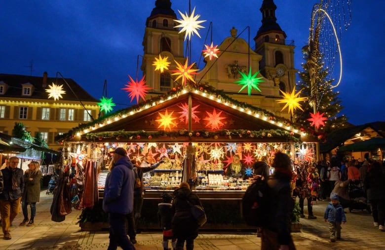 A Christmas market at nighttime has bright star-shaped lights. 