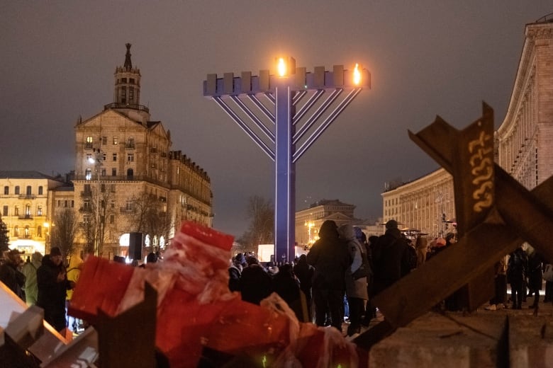 A giant menorah shines in Kyiv among anti-tank gear.