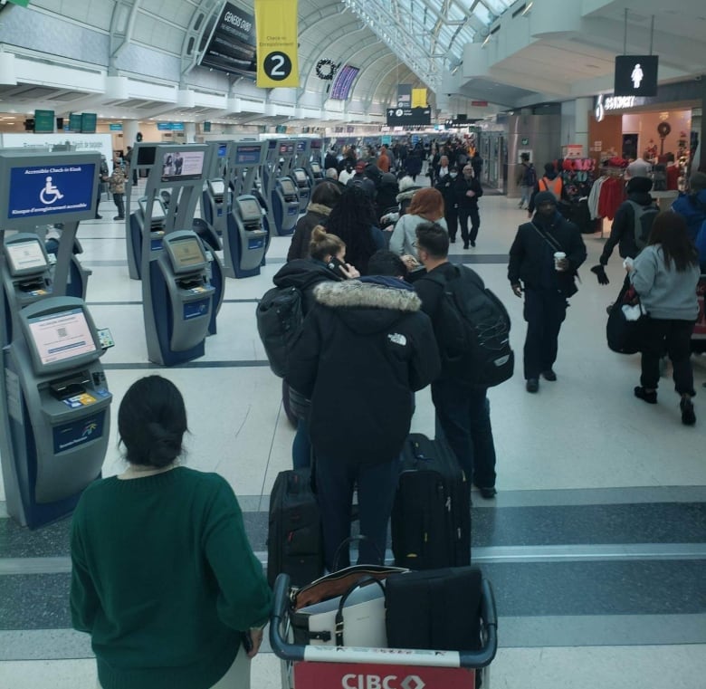 A long line of travellers stands in a Toronto airport.