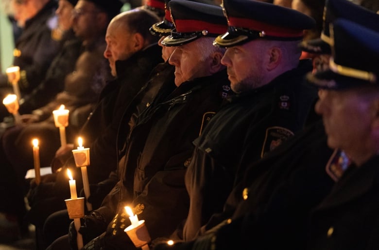 Police officers attend a candlelight vigil for victims of a deadly condo shooting in Vaughan, Ont., on Wednesday, Dec. 21, 2022.