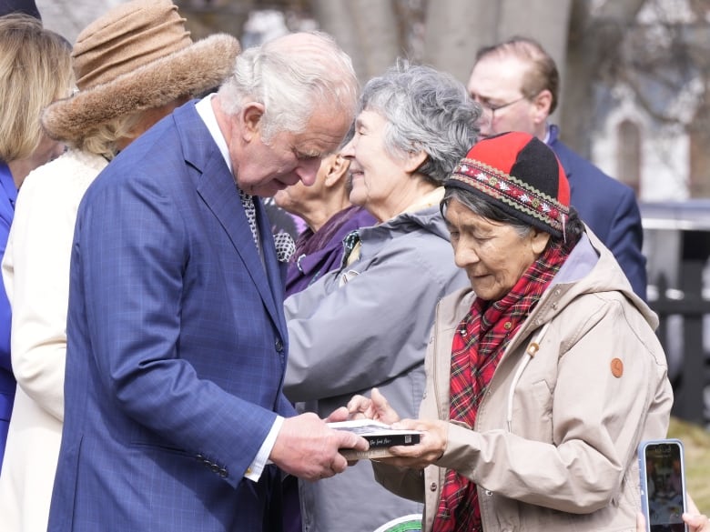 Two people speak with one another as they hold books.