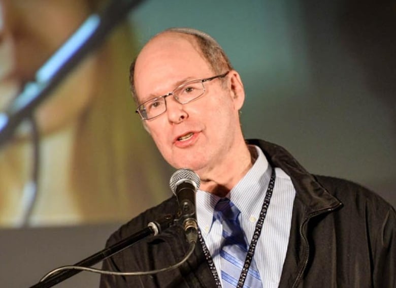 A man is seen speaking at a podium.