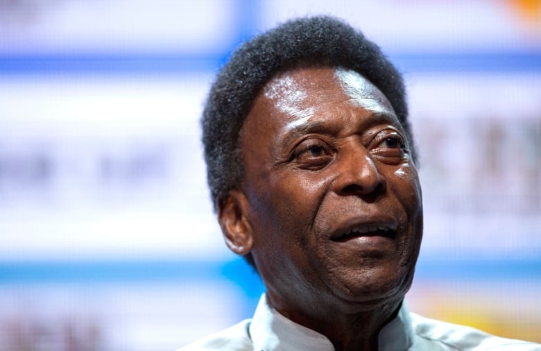 Pele looks skyward while wearing a collared shirt.