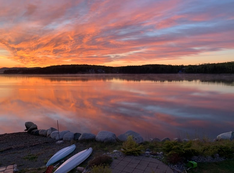 A bright sun rises is reflected in a body of water.