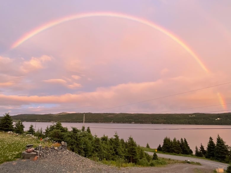 Rainbow over water with a bright sky.