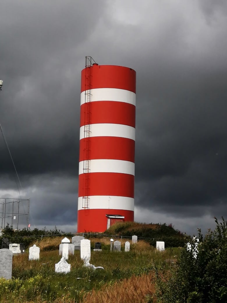 A building similar to a lighthouse stands proud in the midst of a graveyard. 