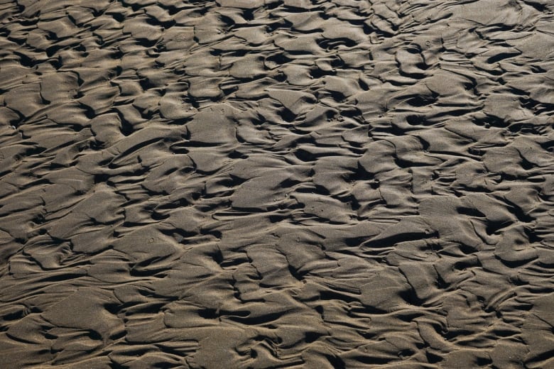 Sand on a beach is resting in an unusual pattern.