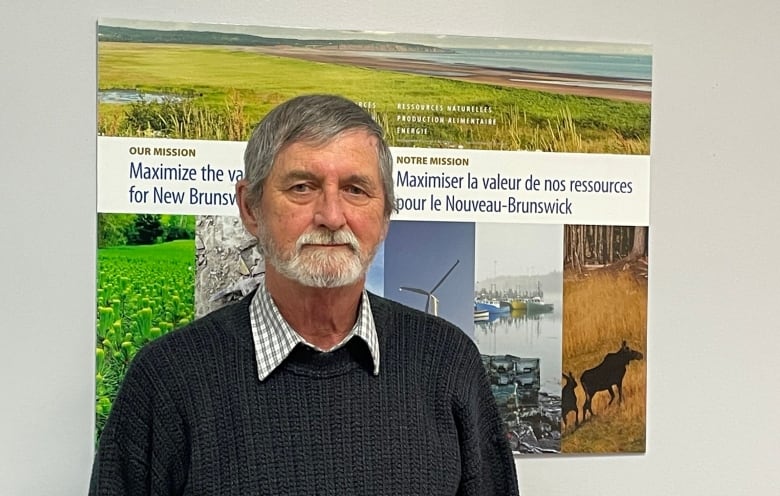 A man stands in front of a poster.