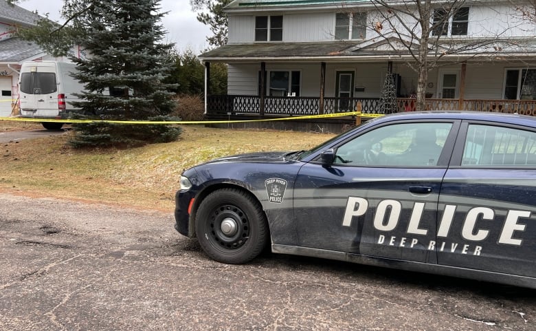 A police cruiser parked on the street in front of a home.