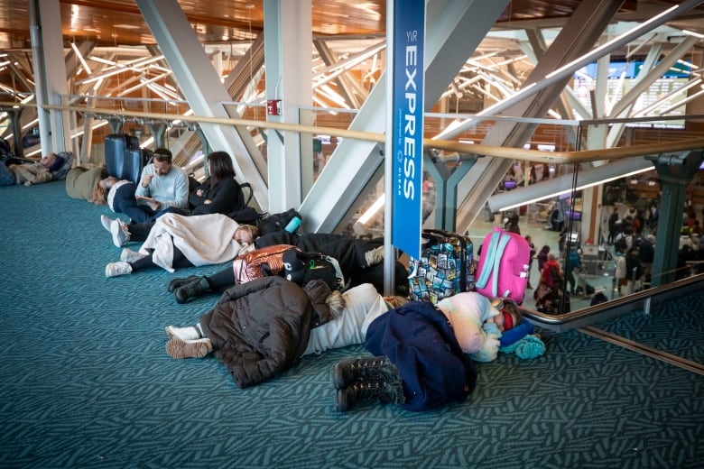 People lie on the ground with jackets covering them as they try to sleep.