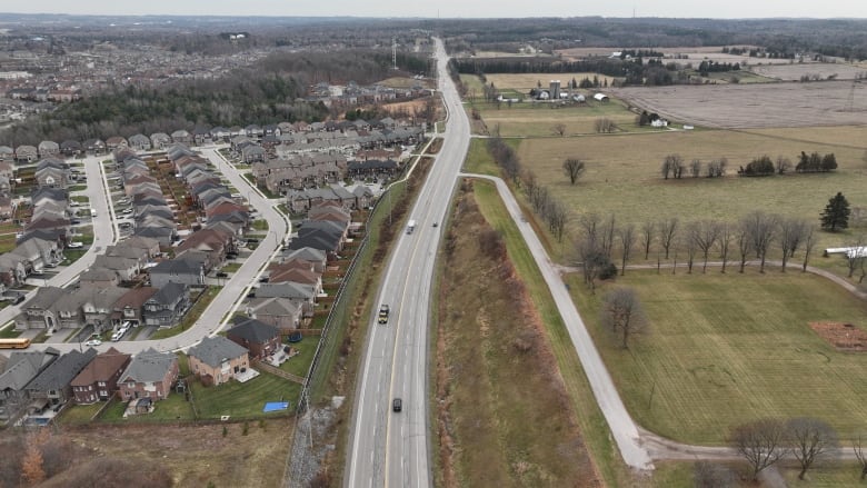 A farm field across the street from a residential subdivision.