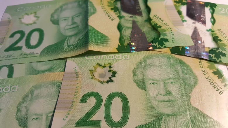 Several green $20 Canadian bank notes with the face of the Queen.