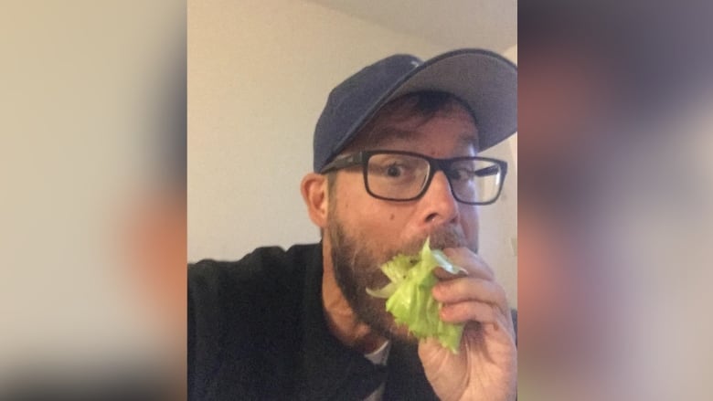 A man eats a lettuce wrap.