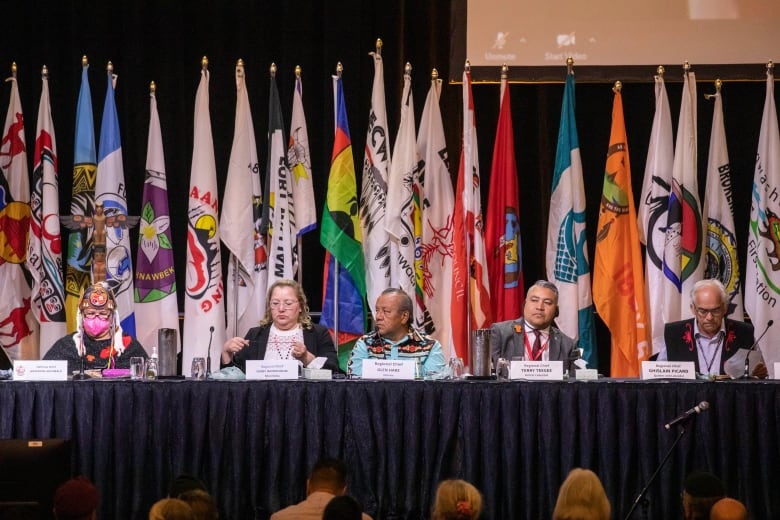 First Nations leader sit together on stage.